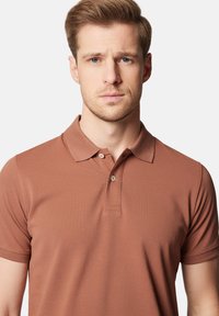 Brązowa koszulka polo z fakturowanej tkaniny, z kołnierzykiem, zapięciem na dwa guziki i krótkimi rękawami, dopasowany krój.