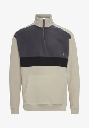 Beige ja tumehall fliispullover pool tõmblukuga kaeluses, esitaskuga ja musta aktsendi ribaga rinna kohal. Pehme tekstuur.