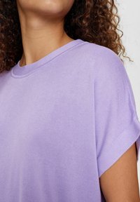 Lila kortärmad topp med avslappnad passform, ribbad textur och rund halsringning med subtila sömdetaljer.