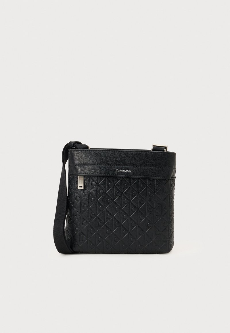 Svart crossover-veske med et teksturert skinneksler som har diamantmønster, justerbar stropp og sølvfarget hardware-detaljer.