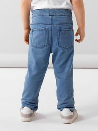 Svijetloplave traper hlače s opuštenim krojem, s dva stražnja džepa, šivenim detaljima i elastičnom waistband. Nosene s bijelim i sivim tenisicama.