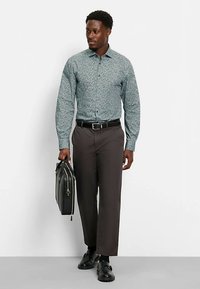 Langärmeliges, hellblaues Hemd mit Blumenmuster, kombiniert mit dunkelbrauner Hose, schwarzem Gürtel, Schuhen und schwarzer Aktentasche.