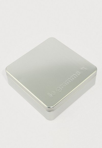 Sølvfarvet rektangulær metalæske med afrundede kanter og "le gramme" præget på låget.