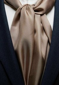 Silke slipsen i en blød, lysbrun farve, intrikat bundet med en glat tekstur, kombineret med en dyb navy blazer stof.