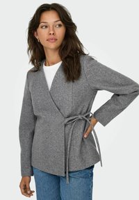 Wikkeljack in zachte grijze stof, met lange mouwen, een strik taille en een V-hals ontwerp. Gecombineerd met denim broeken.