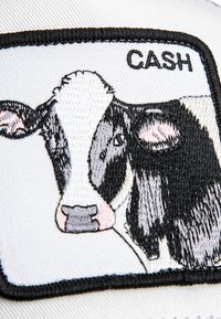 Embroidered patch featuring a black and white cow with the text "CASH," set against a white background with a black border.