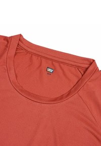 Camiseta atlética roja con cuello redondo, tela texturizada y una etiqueta que muestra la marca y la información del material.