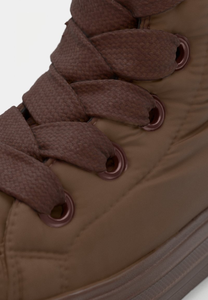 Bruine sneakers met een bovenwerk van textuurstof, dikke bruine veters, metalen oogjes en een rubberen zool met een gelaagd ontwerp.