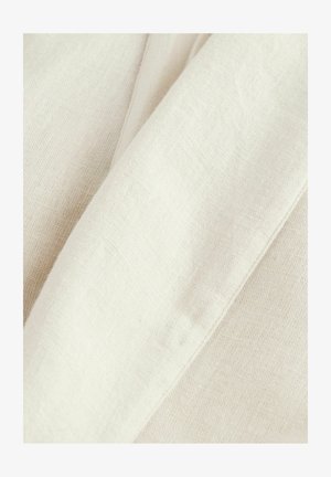 Krém színű lenvászon anyag, amely finom textúrával rendelkezik, sima és enyhén gyűrött területekkel, bemutatva a természetes szálakat.