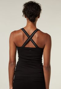 Top a fascia nera con spalline incrociate. Il materiale sembra liscio ed elastico con un design aderente. Stile semplice e minimalista senza decorazioni.