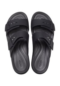 Black sandals made of rubber with two adjustable straps, textured footbed, and a contoured sole. Features small decorative rivets.