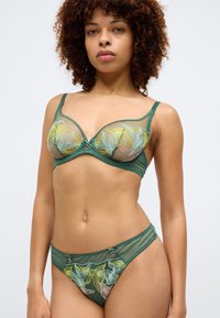 Roheline läbipaistev pesu komplekt, mis sisaldab rinnahoidjat, millel on kollaste ja roosadekirjadega tikitud lillemustrit, mida täiustavad vastavad aluspüksid aktsentidega.