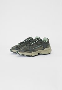 Green mesh sneakers featuring a textured design, reinforced toe, and light green accents. Thick sole with contrasting dark tread pattern.