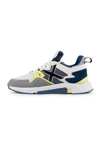 Basket de sport en blanc, gris et bleu marine avec une tige en maille, des accents en daim, une semelle texturée et des détails en jaune vif.