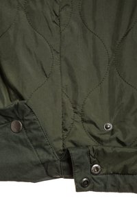 Zielona pikowana kurtka z okrągłymi wzorami przeszycia, napami oraz gładką nylonową fakturą.