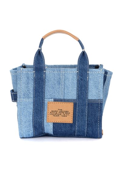 Malá obdélníková taška z patchworku z denimu s kontrastními světlými a tmavými modrými panely, hnědým koženým držadlem a koženou nášivkou vpředu.