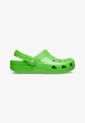 Sabot vert vif à enfiler avec des trous de ventilation, un bord texturé et une bride de talon réglable sur fond blanc.