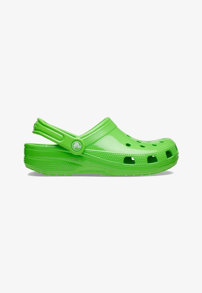 Sabot vert vif à enfiler avec des trous de ventilation, un bord texturé et une bride de talon réglable sur fond blanc.