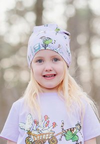 Ljuslila hatt med djurillustrationer, mjukt tyg och avslappnad passform. Barnet bär en matchande ljuslila t-shirt med en tecknad design.