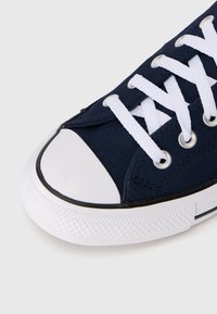 Baskets en toile bleu marine avec embout et semelle en caoutchouc blanc, dotées de lacets blancs et d'œillets en métal. Semelle texturée pour une meilleure adhérence.