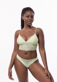 Bralette in pizzo verde chiaro con spalline regolabili e motivo floreale, abbinato a mutandine in stile bikini con dettagli in pizzo.