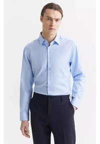 Jasnoniebieska koszula zapinana na guziki, wykonana z gładkiego materiału, z klasycznym kołnierzykiem, długimi rękawami i dopasowanym krojem, w połączeniu z ciemnymi spodniami.