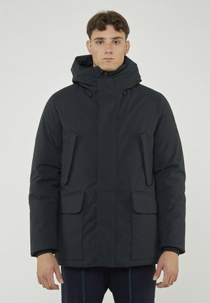 Parka isolante di colore blu navy con cappuccio, dotata di due tasche frontali e una cerniera frontale. Texture liscia con elementi di design minimali.