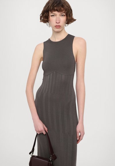 Gray, ribbed-knit dress with a fitted silhouette; features vertical stripes, a crew neckline, and mid-length design. Model holds a burgundy handbag.