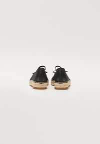 Espadrillas in pelle nera con suola in juta naturale, punta rotonda e lacci decorativi sul retro, con una finitura testurizzata.
