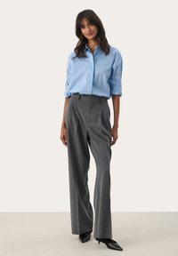 Light blue button-up shirt; gray pinstriped trousers; smooth fabric; tailored fit; high-waisted design; paired with black heeled shoes.