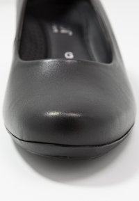 Schwarze Leder-Ballettschuhe mit runder Zehenform, glatter Textur und leichtem Glanz auf dem Obermaterial. Merkmale sind minimale Nähte und eine gepolsterte Innensohle.