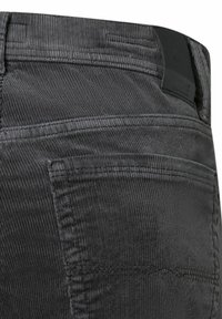 Graue Cordhosen mit gerippter Textur, fünf Taschen-Design und einem schwarzen Taillenschild. Genähte Details entlang der Nähte.