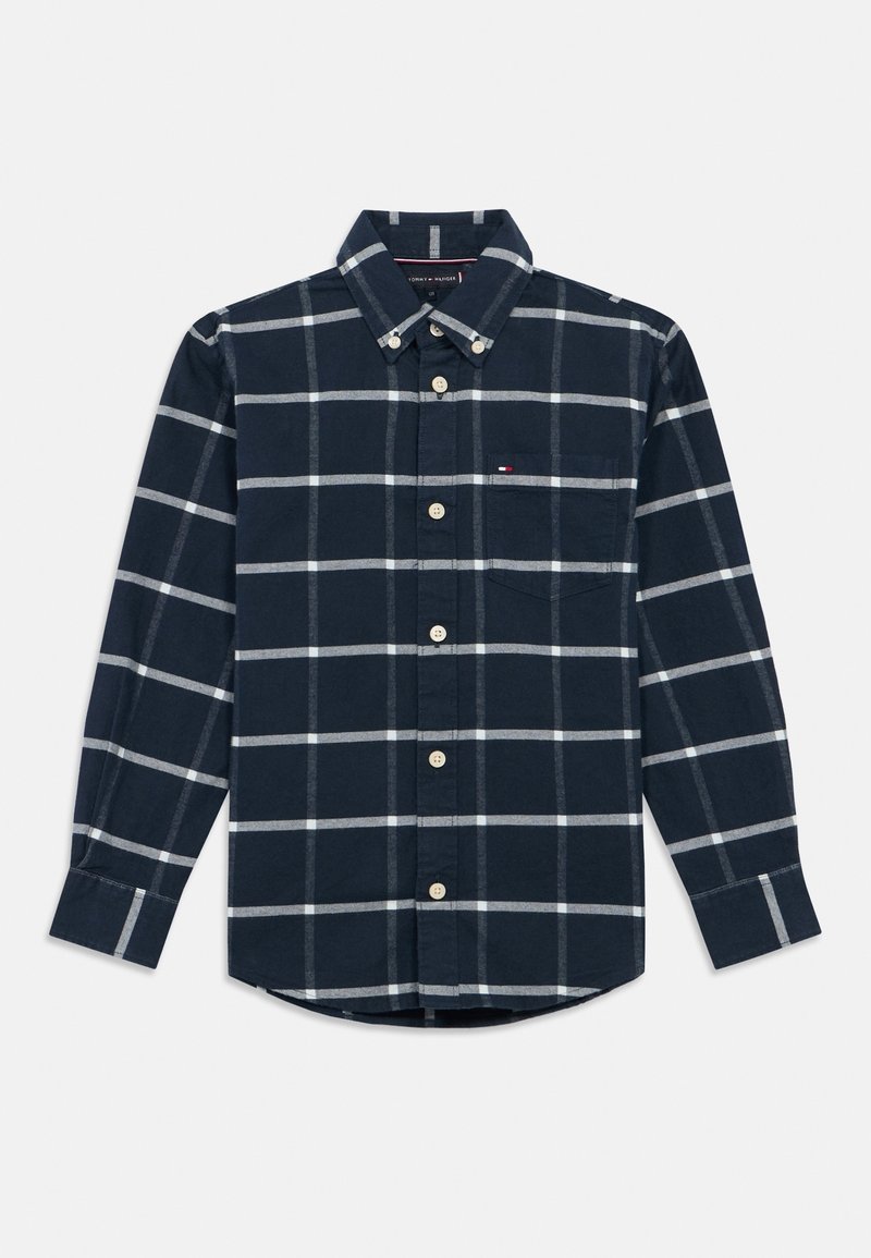 Chemise bleu marine à manches longues boutonnée avec motif à carreaux blanc et gris et une poche poitrine sur fond uni.
