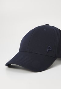 Námornícka baseballová čiapka s prehnutým okrajom, vyrobená z hladkej látky, s malým vyšitým logom "P" na prednej ľavej strane.