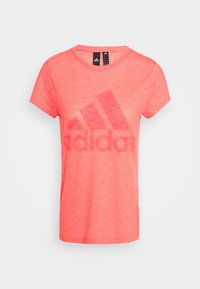 Tričko s krátkým rukávem a kulatým výstřihem v melírované korálové barvě, s velkým bílým logem Adidas a měkkou, lehkou texturou látky.