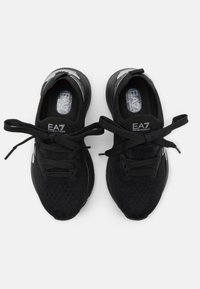 Černé pletené tenisky s dělenými tkaničkami, texturovaným svrškem a gumovou podrážkou. Na jazyku a boku jsou detaily s logem.