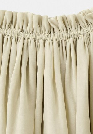 Tela beige recogida con borde superior elástico que crea pliegues verticales espaciados de manera uniforme.