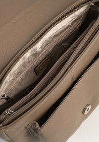 Interno di una borsa in pelle marrone, caratterizzato da più scomparti, chiusure a zip morbide e una fodera in tessuto soffice con dettagli di marca discreti.
