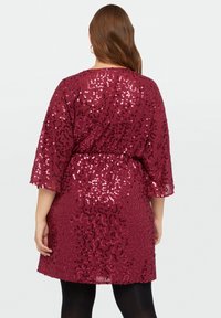Robe bordeaux ornée de sequins, avec une coupe décontractée, des manches courtes et une taille élastique, présentant une surface texturée et brillante.