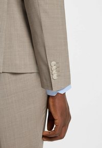 Beige kostymsleeve med fyra ljusa knappar, med en blå rutad manschett under. Slät, texturerad tyg med skräddarsydd passform.
