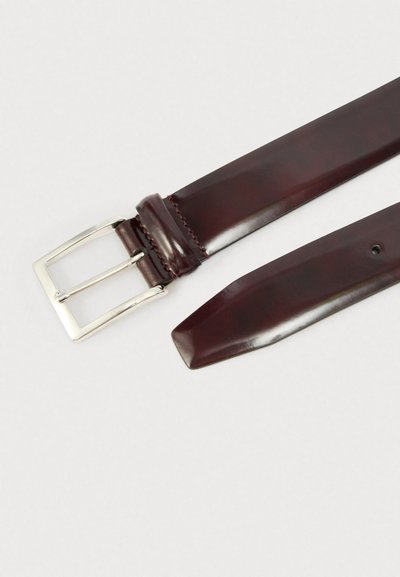 Καφέ δερμάτινη ζώνη με ασημένια μεταλλική ορθογώνια αγκράφα, λεία υφή, μυτερή άκρη και ραφές κοντά στην αγκράφα.