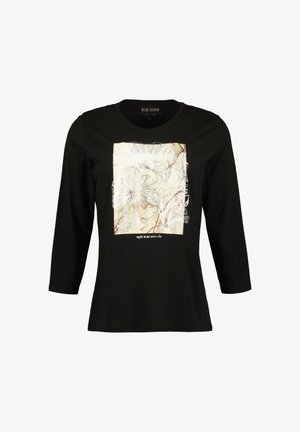 Černé dlouhé tričko s dlouhým rukávem, které zdobí čtvercový krémový grafický motiv s květinovým lineárním uměním a textem "styl je postoj" na spodní části.