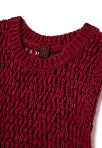 Top senza maniche lavorato a maglia rossa con un motivo a trama aperta e scollo rotondo, con un'etichetta nera e rossa attaccata.