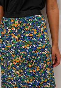 Falda con estampado floral que presenta tonos azules, verdes, naranjas y blancos. Cintura elástica negra, de longitud hasta la rodilla, con textura de tela suave y ligera.