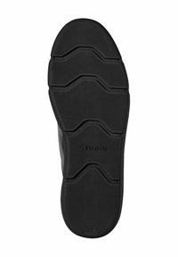 Suola di scarpa in gomma nera con una superficie texturizzata caratterizzata da scanalature e cordoli. Il logo "Tamaris" è impresso vicino al tallone.