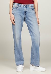 Jeans de denim azul claro con un ajuste holgado, piernas rectas, costuras visibles y una cintura que presenta un cierre de botón y cremallera.