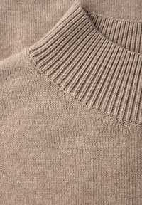 Beige gestrickter Pullover mit einem gerippten Kragen und glatter Textur. Der Stoff hat ein einheitliches Muster mit subtilen Farbvariationen.