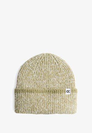 Bonnet tricoté en vert olive clair, avec un revers côtelé et une étiquette blanche portant un logo noir. Texture douce avec un motif de tricot épais.