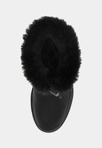 Botte d'hiver noire avec une épaisse doublure en fourrure duveteuse autour de l'ouverture et un dessus en cuir lisse, vue de dessus.