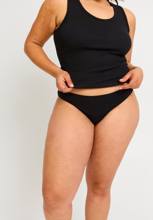Débardeur noir à côtes associé à un bas de bikini noir. Texture lisse, design ajusté et détails de taille réglable.